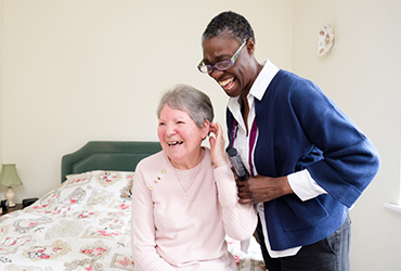 CAREGiver brushing elderly lady's hair and laughing