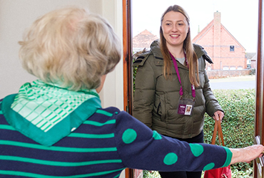Elderly lady welcomes a Home Instead CAREGiver into home