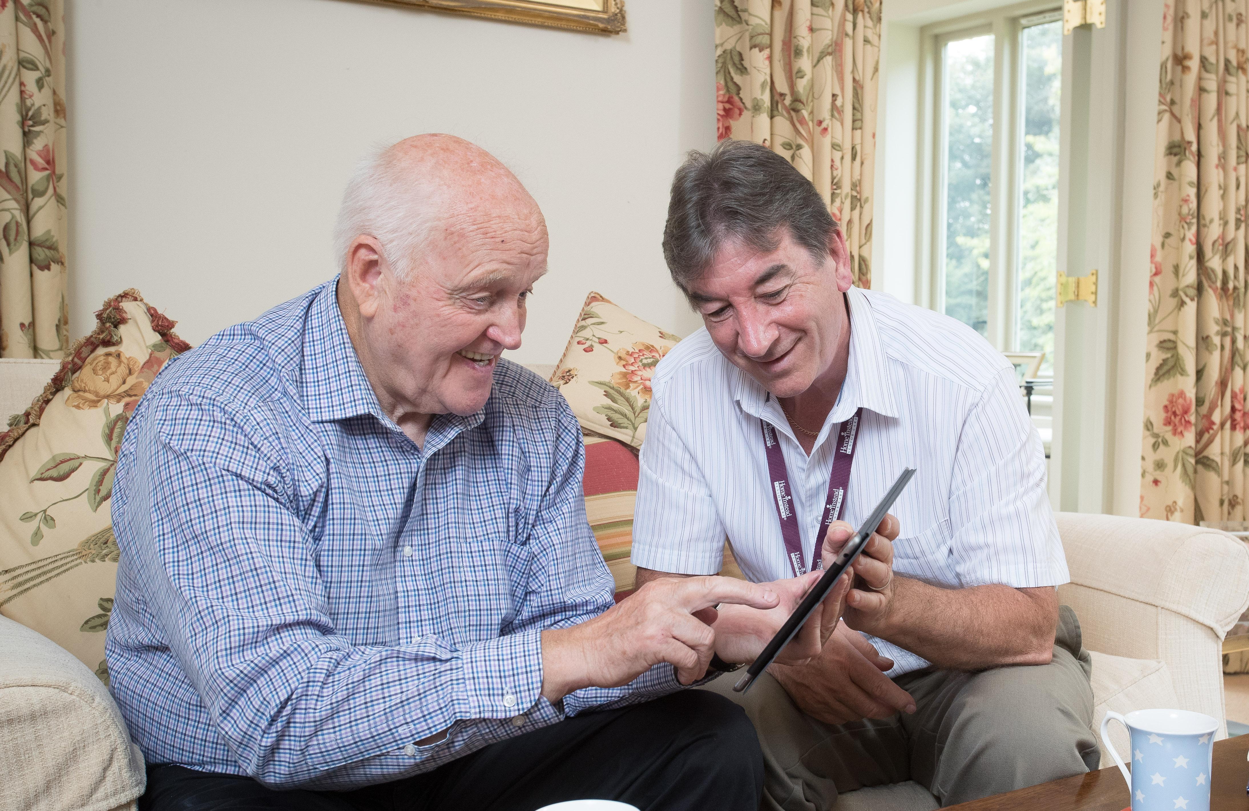 Photo of CAREGiver helping older man avoid online scams on iPad