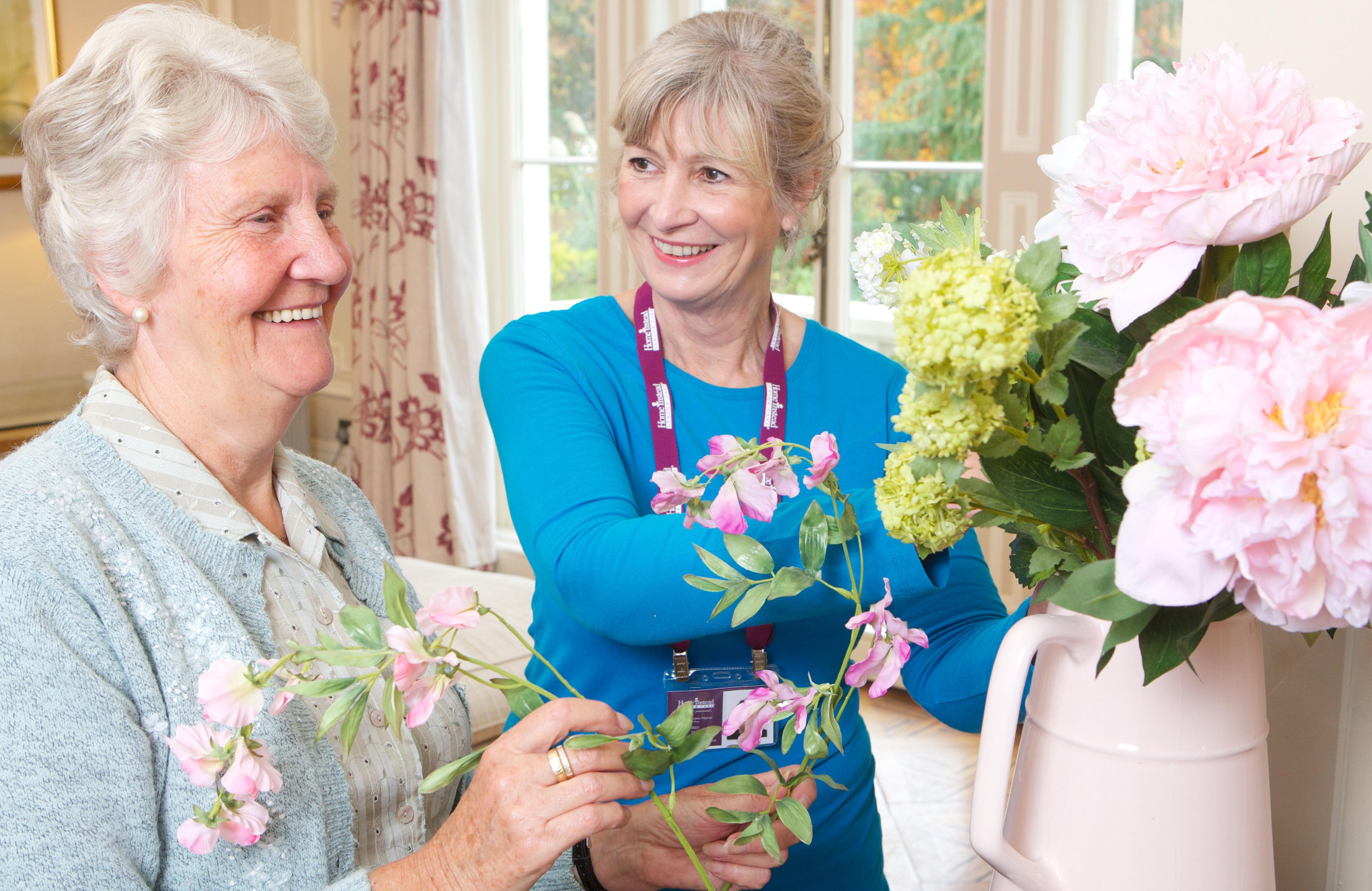 Caregiver helping elderly lady with flowers
