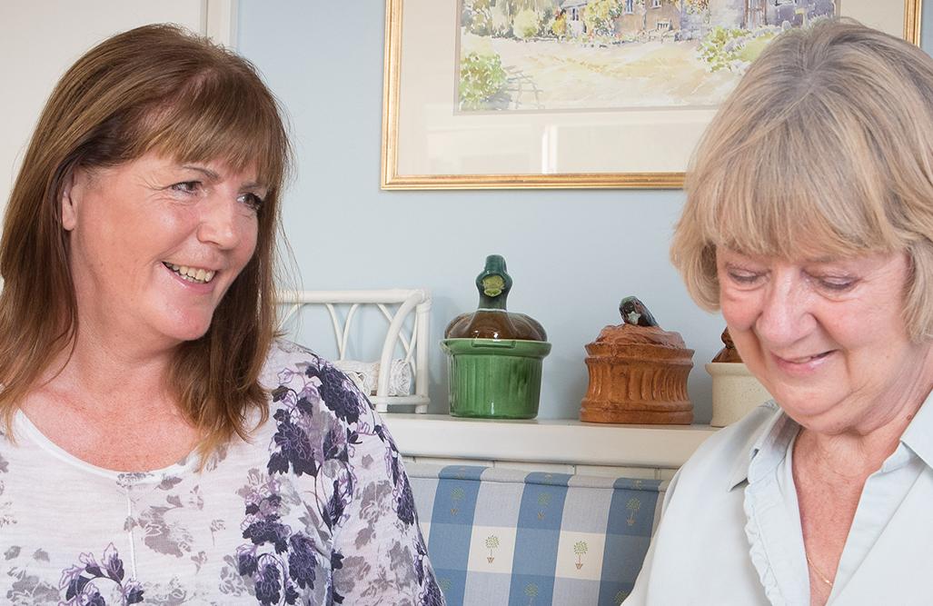 CAREGiver and elderly lady laughing together in the kitchen